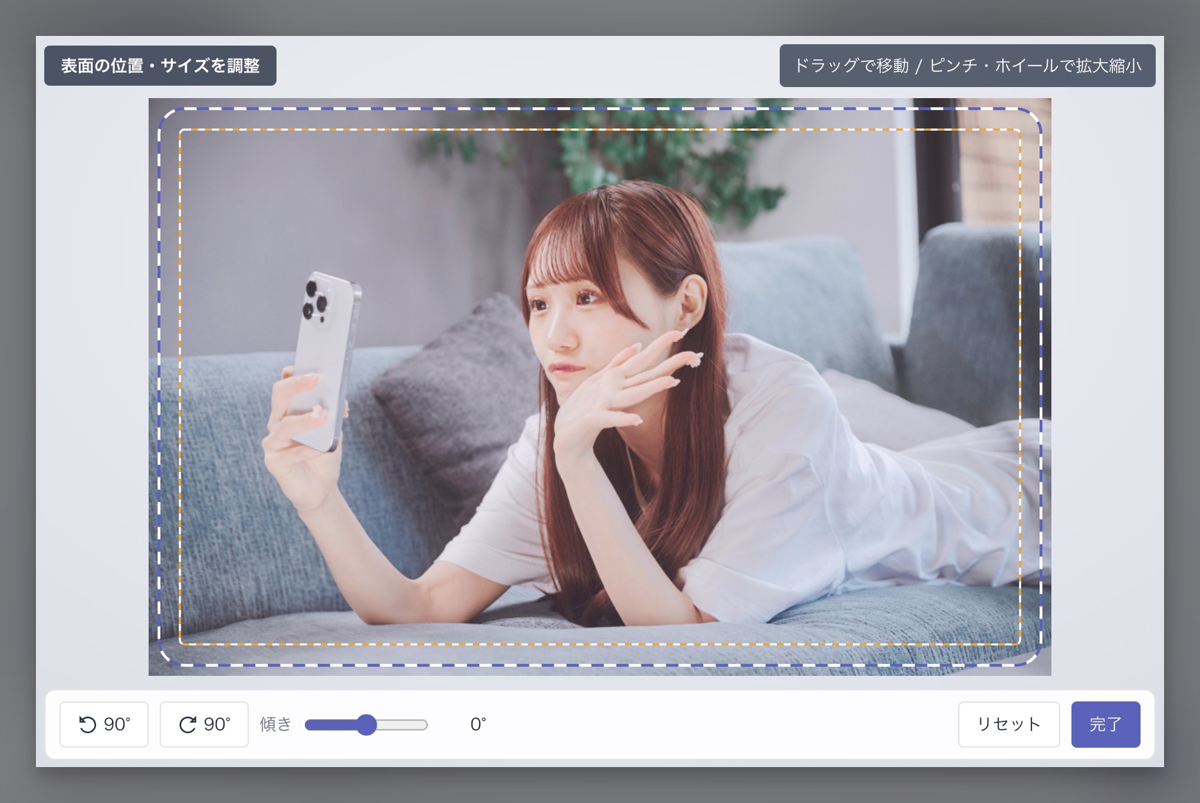 シミュレーターの調整画面。アップロードした画像の上に、青の破線（仕上がりライン）とオレンジの破線（デザインライン）が重ねて表示され、画面下部に回転・傾き・リセット・完了の操作バーが並んでいます。